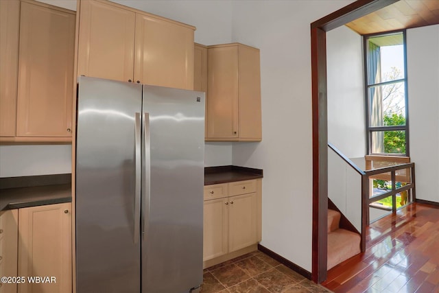 kitchen featuring freestanding refrigerator, dark countertops, baseboards, and cream cabinets