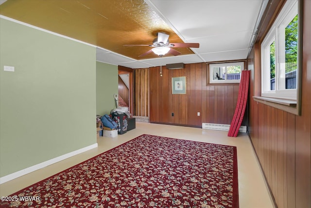 spare room with wooden walls, baseboards, ceiling fan, and baseboard heating
