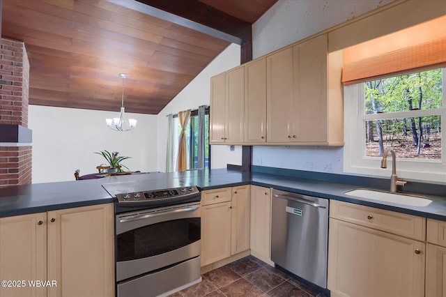 kitchen with dark countertops, lofted ceiling with beams, cream cabinets, a sink, and stainless steel appliances