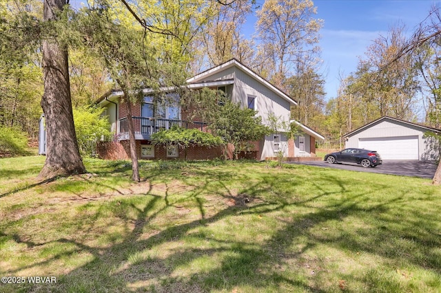 view of property exterior featuring a detached garage, a lawn, a deck, and brick siding