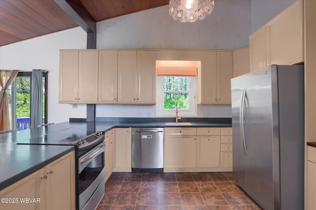 kitchen featuring stainless steel appliances, a sink, vaulted ceiling with beams, and cream cabinetry