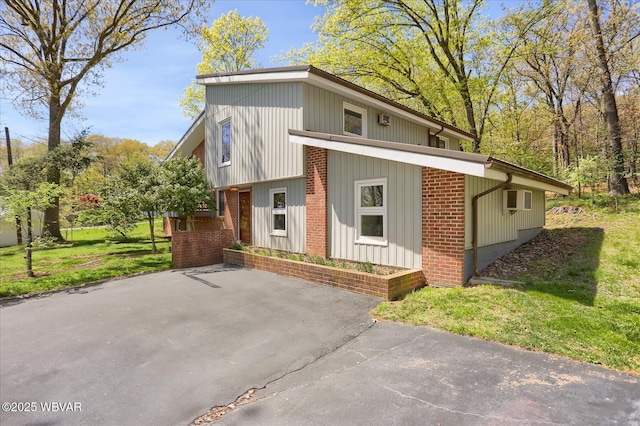 view of side of home featuring a lawn, a wall mounted AC, and brick siding