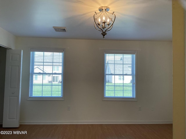 unfurnished room featuring dark hardwood / wood-style floors and an inviting chandelier