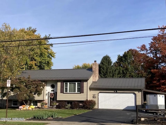 view of front of home featuring a garage, metal roof, driveway, a chimney, and a front yard