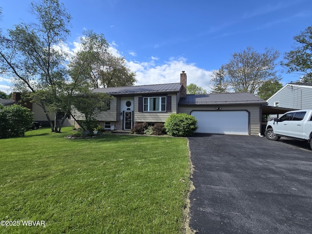 raised ranch with a chimney, a garage, a front lawn, metal roof, and asphalt driveway
