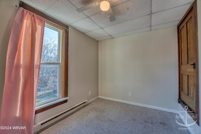 empty room with light carpet, a drop ceiling, baseboard heating, and ceiling fan