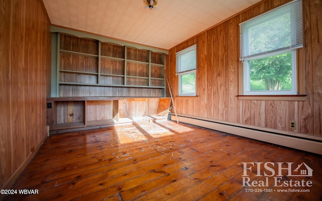 spare room with wood ceiling, built in shelves, a baseboard heating unit, wooden walls, and hardwood / wood-style flooring