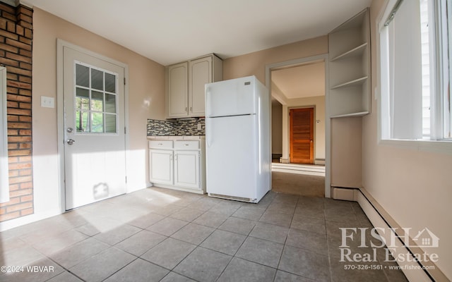 kitchen featuring decorative backsplash, light tile patterned floors, white refrigerator, and baseboard heating