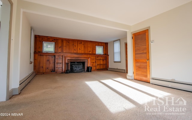 unfurnished living room with baseboard heating, wood walls, and light colored carpet