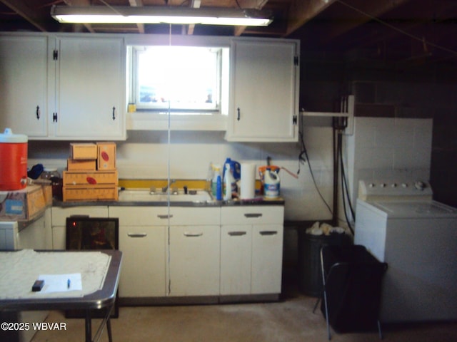 kitchen featuring washer / clothes dryer, sink, and white cabinets