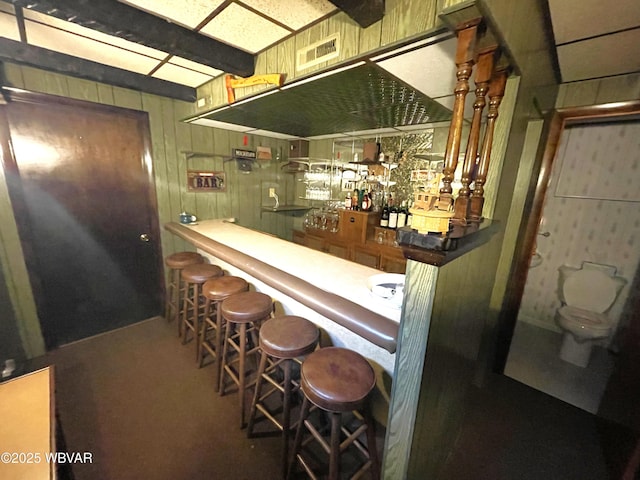 bar featuring wooden walls and beam ceiling