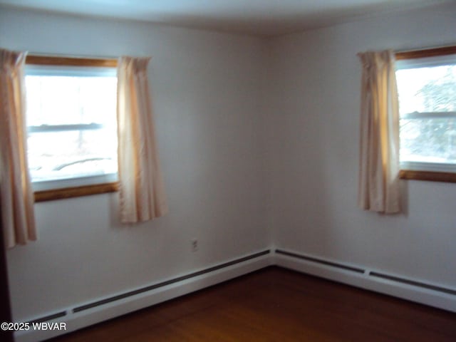 empty room with baseboard heating and dark wood-type flooring