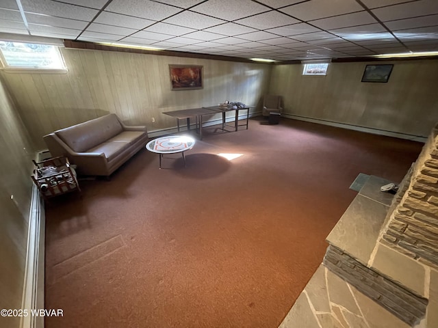 unfurnished room featuring a paneled ceiling, wooden walls, and dark colored carpet