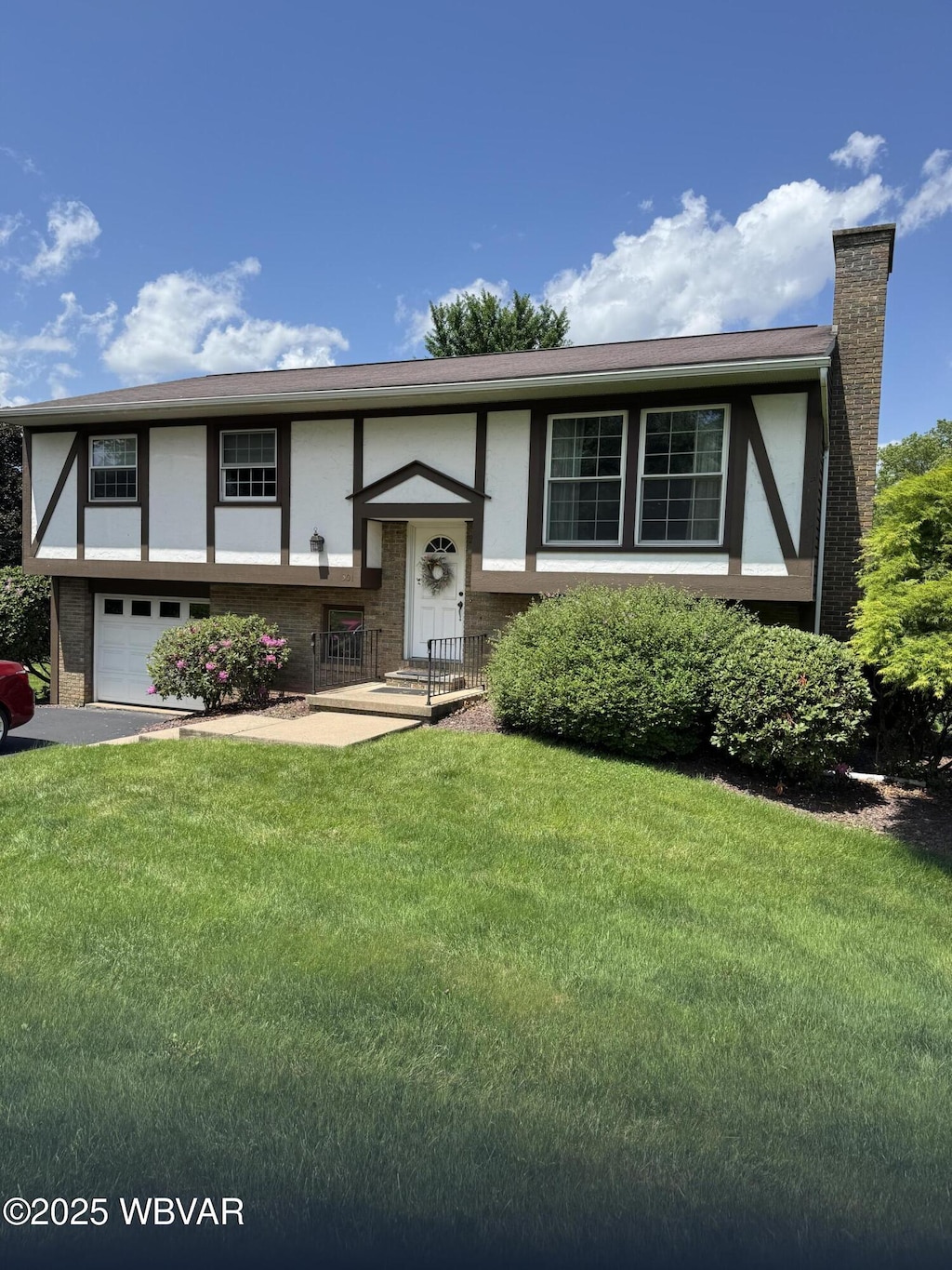 301 Charles Rd, Muncy, PA 17756 - view of front of house featuring stucco siding, an attached garage, a front lawn, a chimney, and asphalt driveway