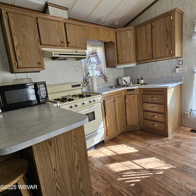 kitchen with black microwave, under cabinet range hood, vaulted ceiling, light wood-type flooring, and white gas range