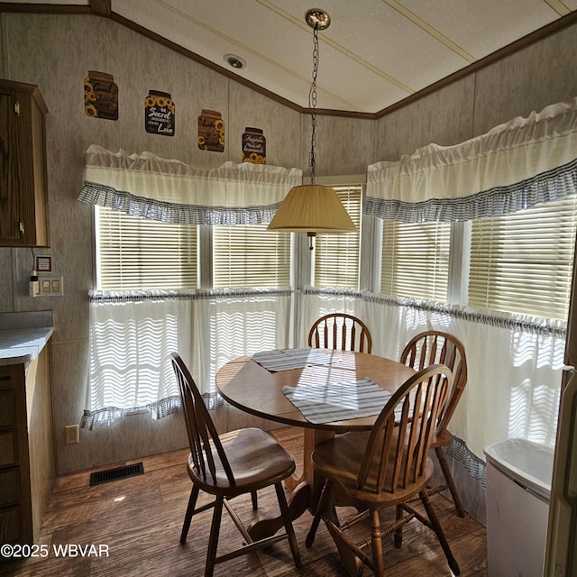 dining room featuring plenty of natural light, visible vents, vaulted ceiling, and wood finished floors