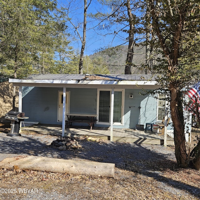 back of house with covered porch and metal roof