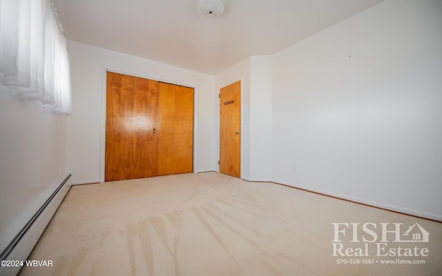 unfurnished bedroom with carpet floors, a closet, and a baseboard heating unit