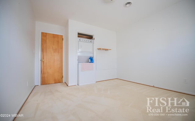 unfurnished room featuring carpet flooring and stacked washing maching and dryer