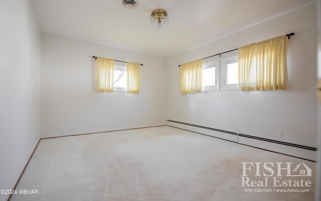 carpeted spare room with baseboard heating and a wealth of natural light