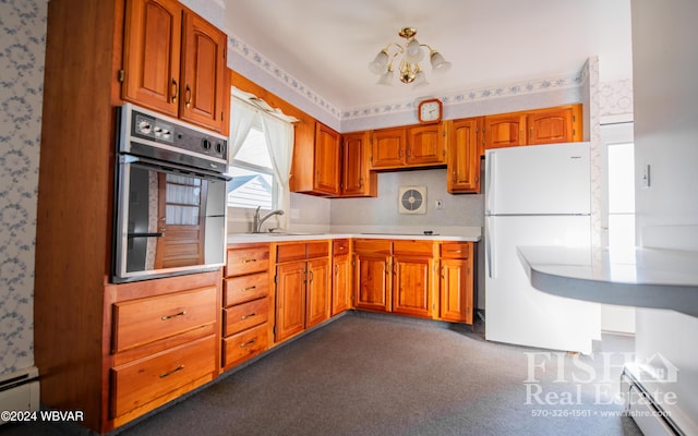 kitchen featuring dark carpet, stainless steel oven, sink, white refrigerator, and a chandelier