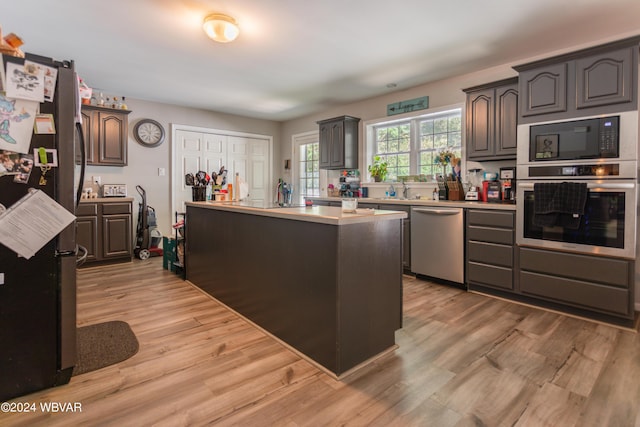 kitchen with appliances with stainless steel finishes, light wood-type flooring, and a kitchen island