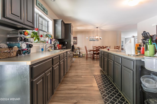 kitchen featuring sink, hanging light fixtures, light wood-type flooring, a notable chandelier, and a kitchen island