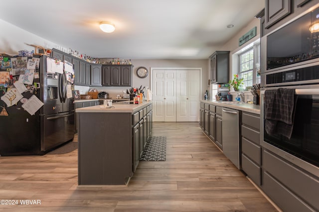 kitchen featuring a kitchen island, sink, stainless steel appliances, and light hardwood / wood-style flooring