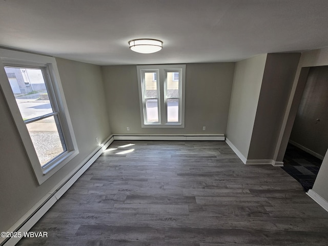 spare room featuring a baseboard heating unit, a healthy amount of sunlight, dark wood-type flooring, and a baseboard radiator