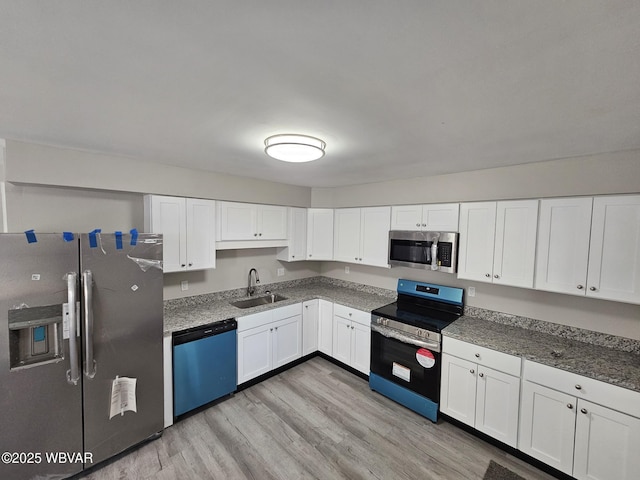 kitchen with light wood-type flooring, a sink, white cabinetry, and appliances with stainless steel finishes