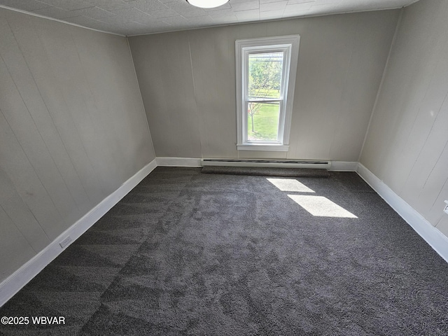 unfurnished room with dark carpet, baseboards, and a baseboard heating unit