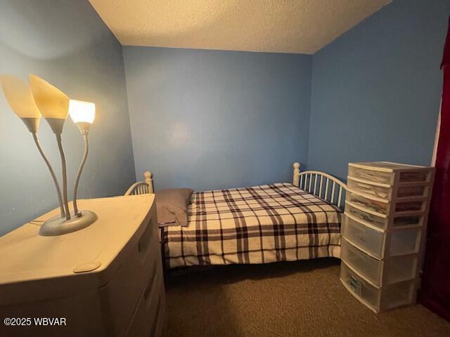 bedroom with dark carpet and a textured ceiling