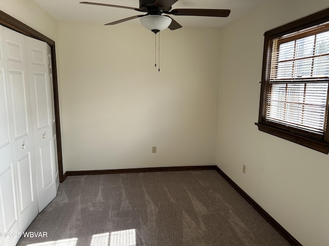 unfurnished bedroom featuring dark colored carpet, ceiling fan, and a closet