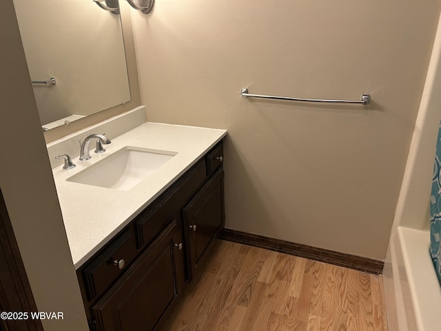 bathroom with wood-type flooring, a bathing tub, and vanity