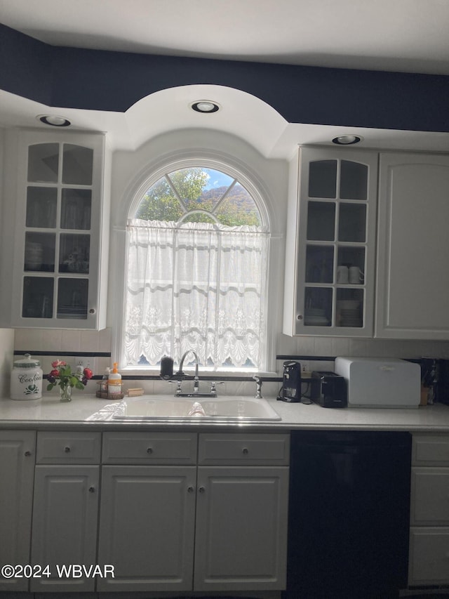 kitchen featuring decorative backsplash, black dishwasher, and sink