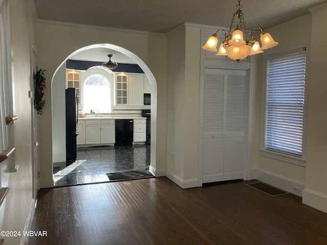 entrance foyer with dark wood-type flooring, sink, ornamental molding, a textured ceiling, and a notable chandelier