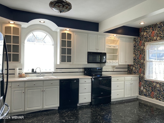 kitchen with sink, white cabinetry, and black appliances