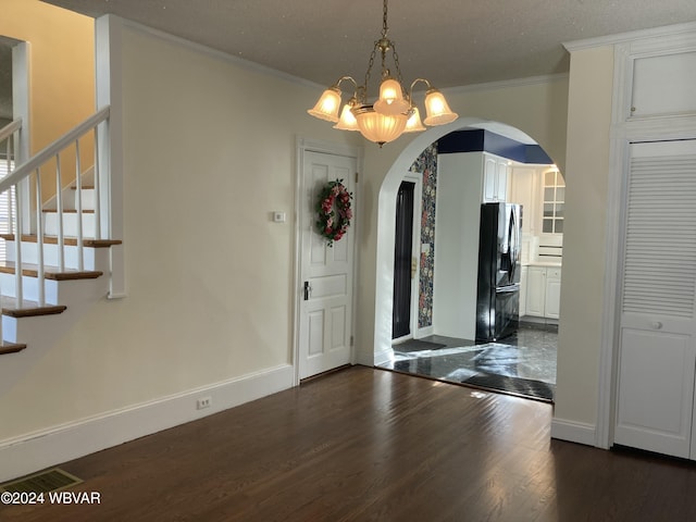 foyer with a notable chandelier, dark hardwood / wood-style floors, and ornamental molding