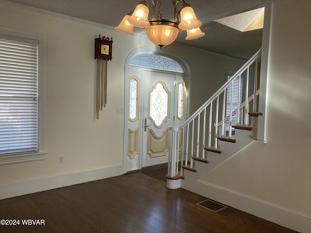 entrance foyer with dark hardwood / wood-style flooring, ornamental molding, a textured ceiling, and a chandelier