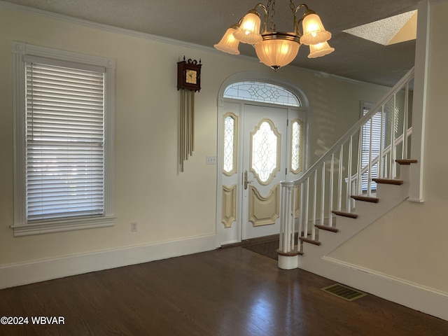 entryway with dark hardwood / wood-style flooring, an inviting chandelier, a textured ceiling, and ornamental molding