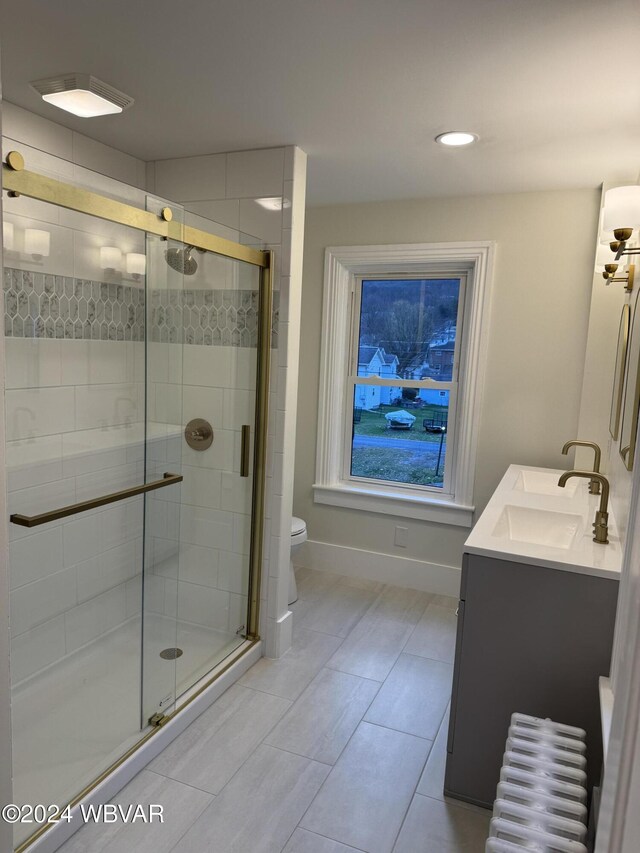 bathroom featuring vanity, radiator, tile patterned floors, toilet, and an enclosed shower