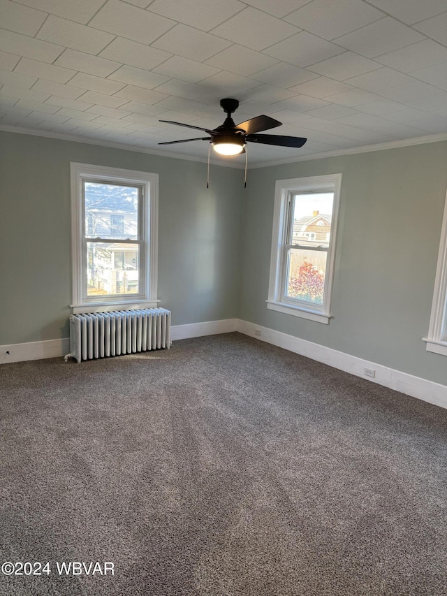 carpeted spare room featuring radiator heating unit, ornamental molding, a healthy amount of sunlight, and ceiling fan