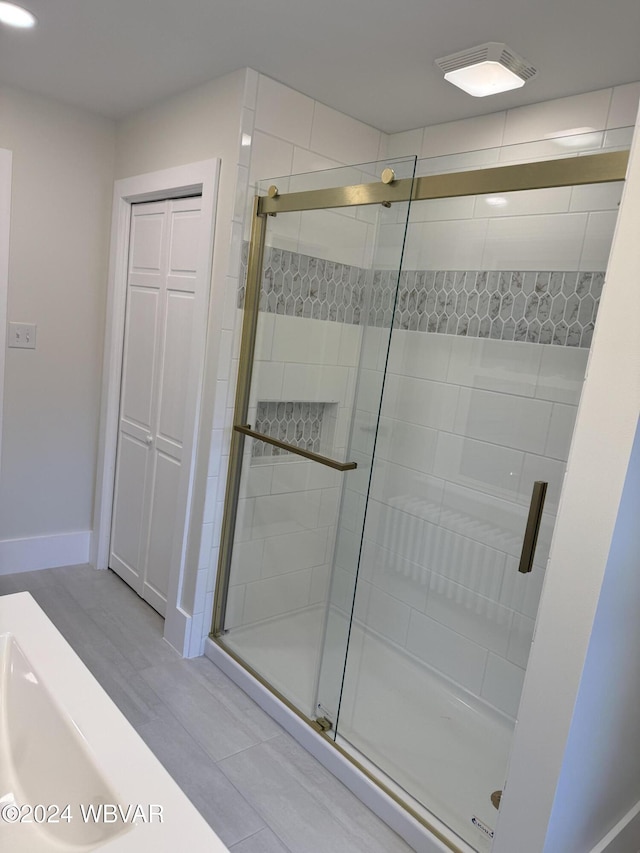 bathroom with an enclosed shower and wood-type flooring