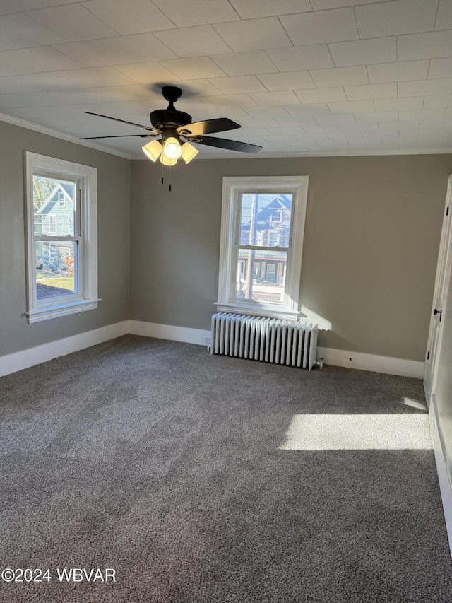 carpeted spare room featuring ceiling fan, a healthy amount of sunlight, crown molding, and radiator