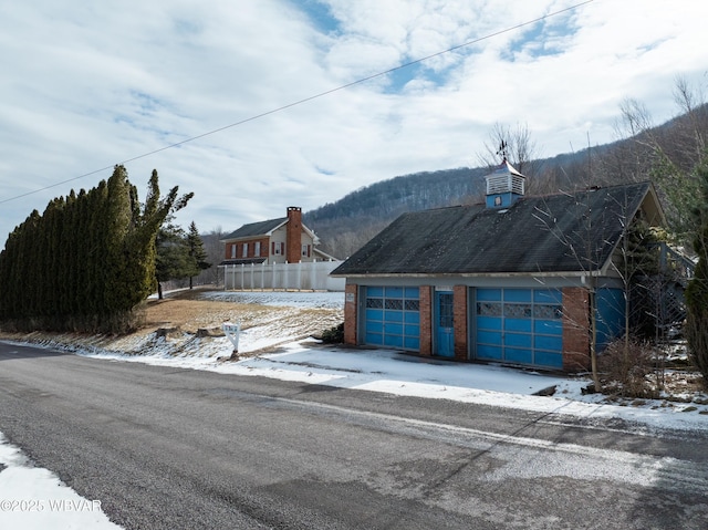 exterior space with a detached garage, a mountain view, and brick siding