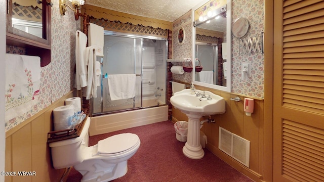 full bathroom featuring a wainscoted wall, toilet, visible vents, and wallpapered walls