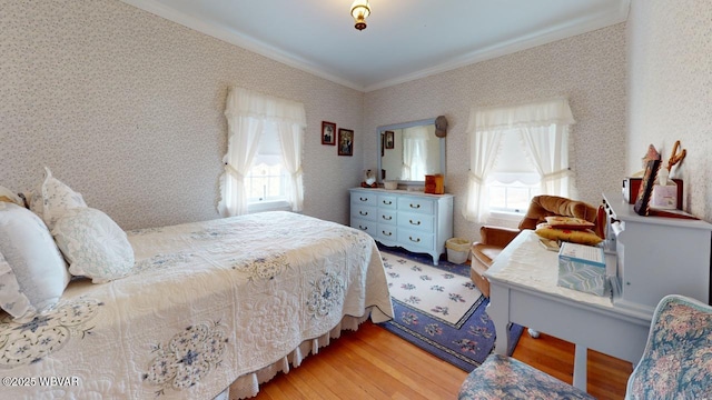 bedroom featuring ornamental molding, wood finished floors, multiple windows, and wallpapered walls