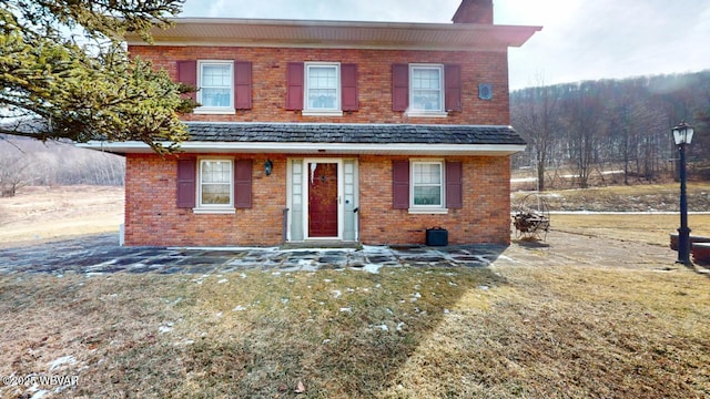 view of front of property with a chimney and brick siding