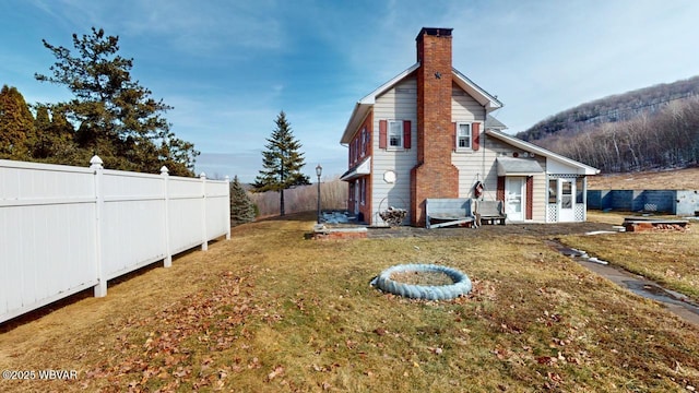 view of home's exterior featuring a fenced backyard, a lawn, and a chimney