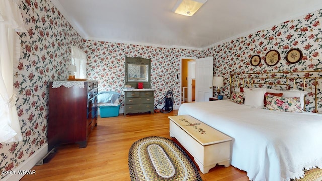 bedroom featuring crown molding, baseboards, wood finished floors, and wallpapered walls